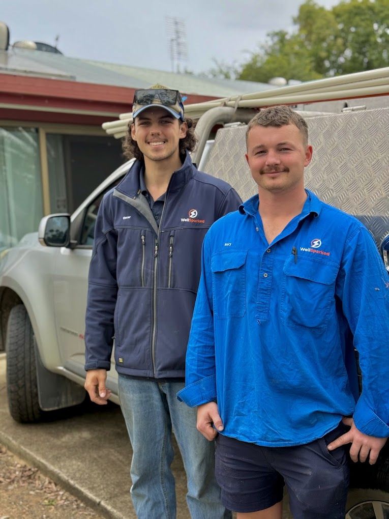 Oscar and Rory in Well Sparked uniforms beside the work ute